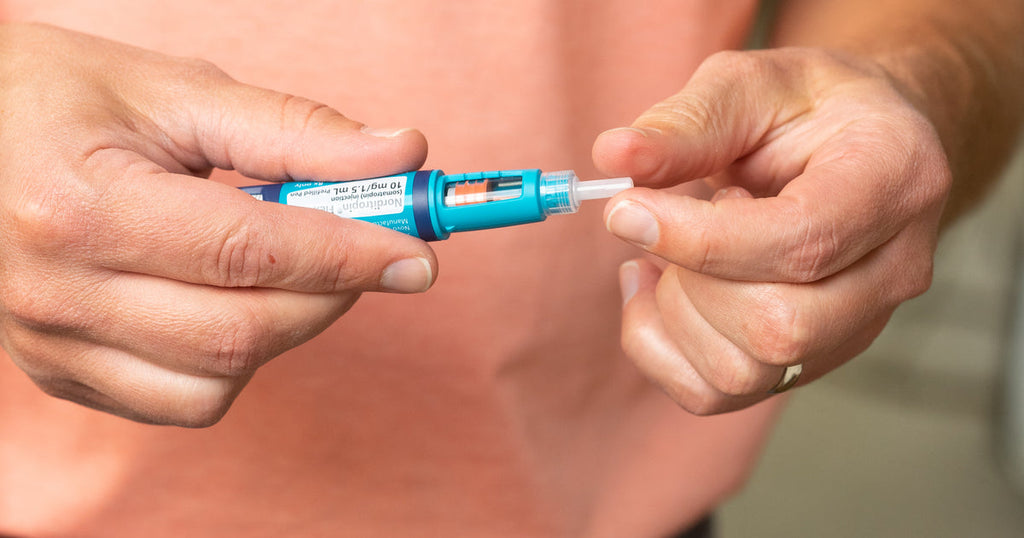 Hands attaching a new pen needle to a multi-dose medication pen