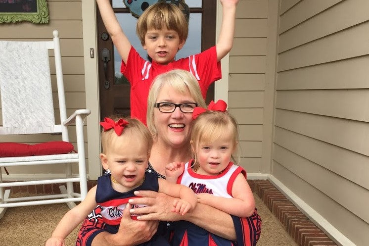 A woman smiling with three children on a porch